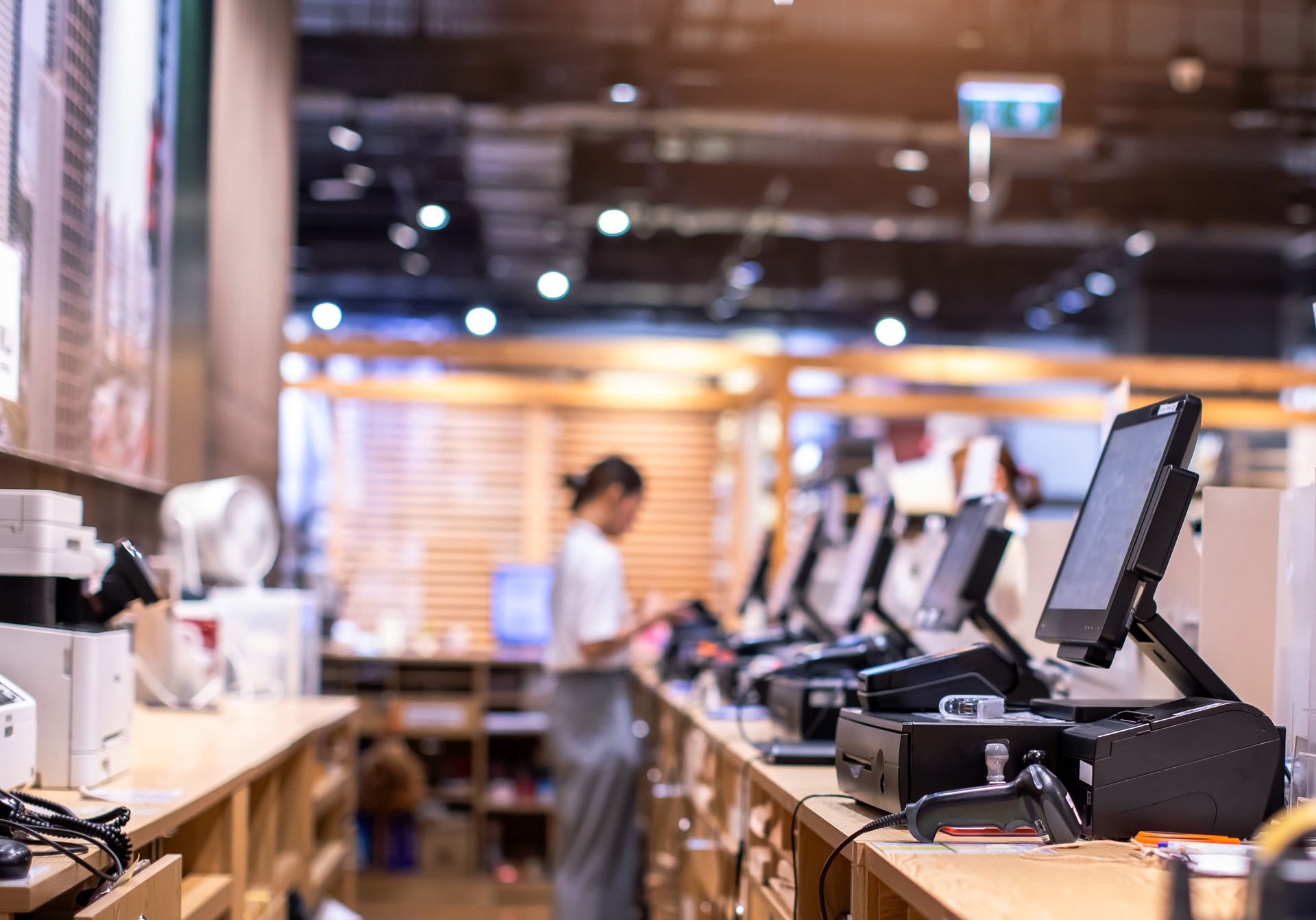 Selective focus to edge of POS machine with blurry cashier staff receive orders from customers at counter service in restaurant or cafe or department store.
